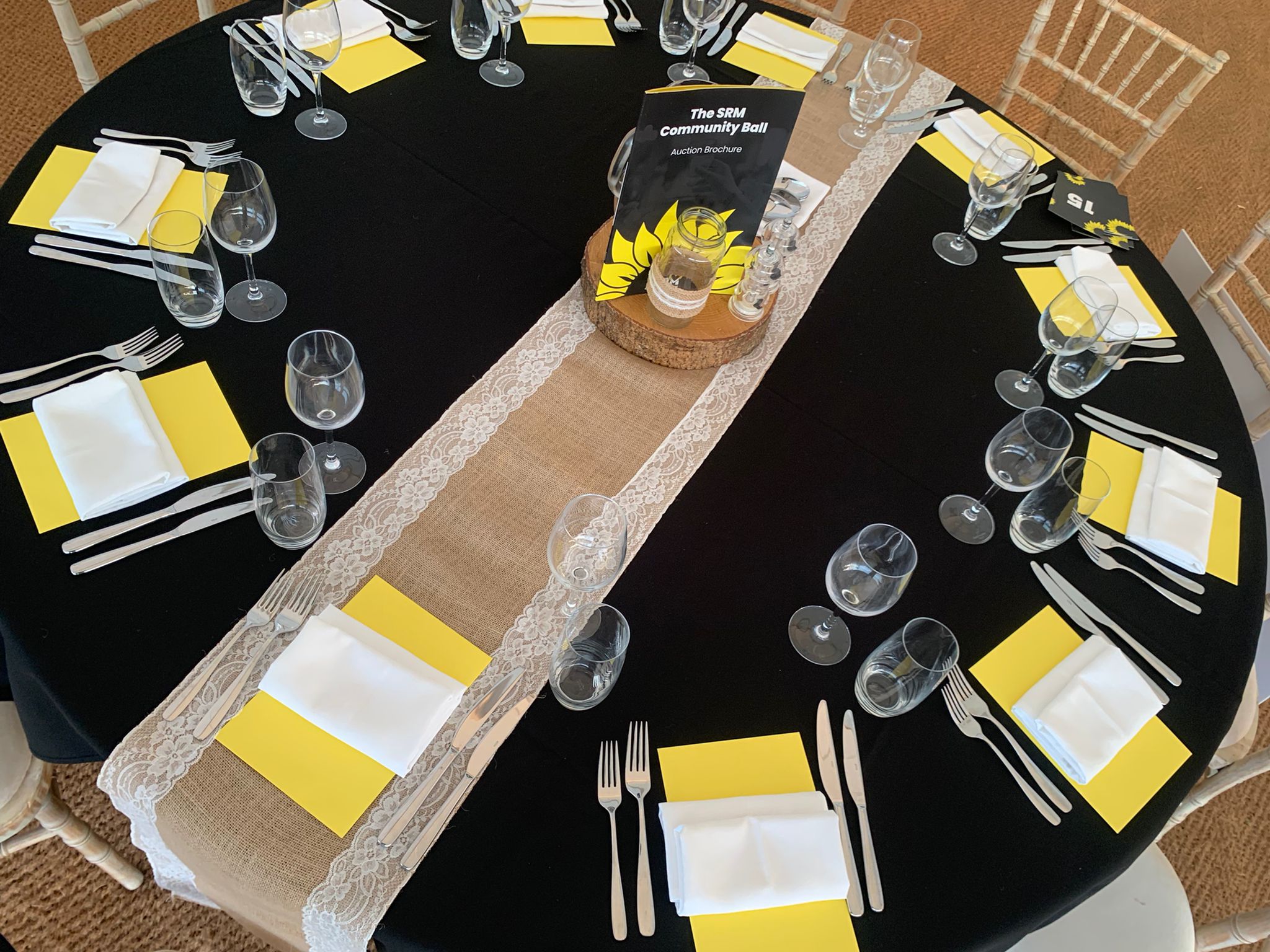 Round dinner table from the event, which is branded black and yellow, with a auction brochure in the middle.